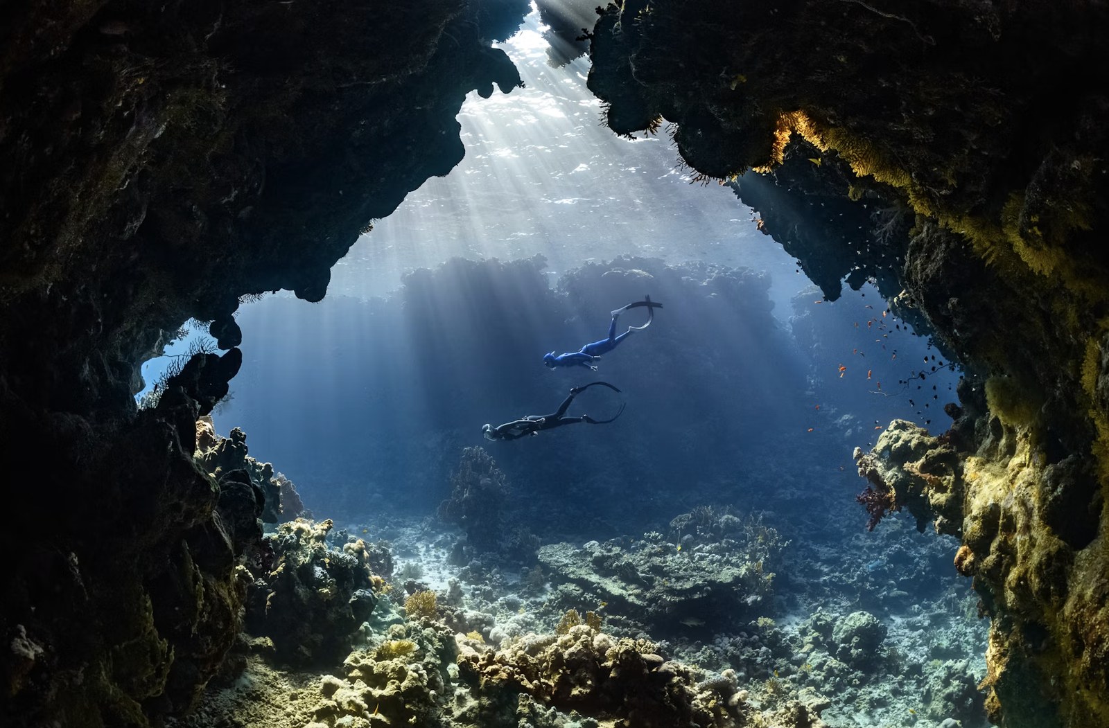 Dramatic underwater coral cave with sunbeams piercing through the opening