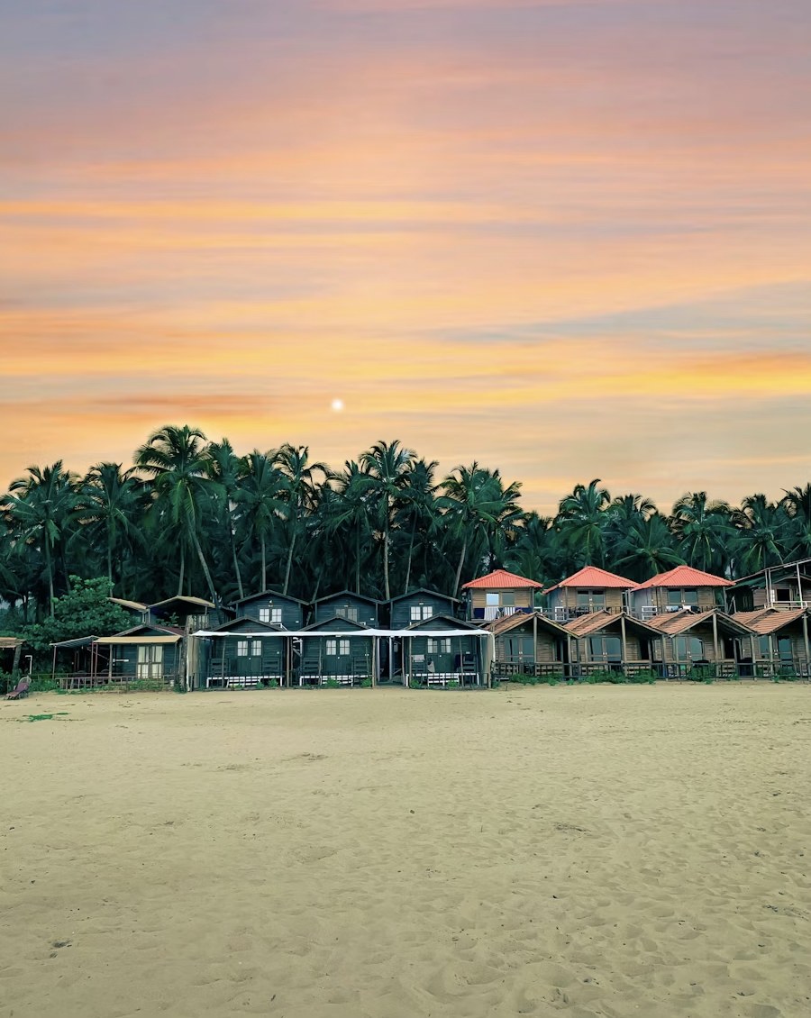 Serene sunset hues over coastal beach shacks and wide sandy shores