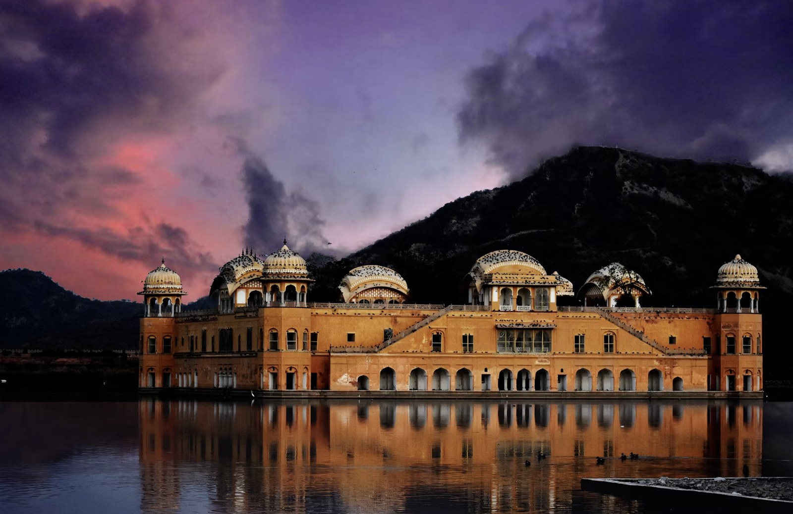 Floating Jal Mahal water palace glowing brilliantly amidst twilight reflections