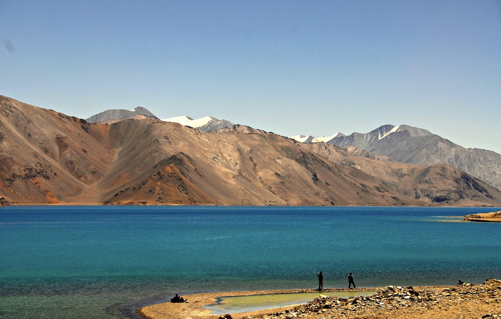 Vibrant color-shifting turquoise waters of Pangong Tso framed by rugged barren peaks