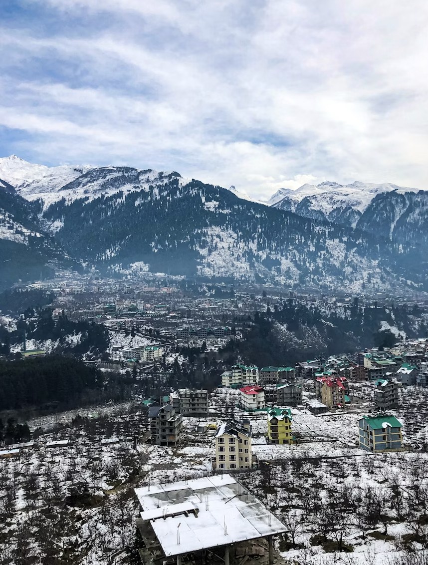 Panoramic vista of snow-blanketed Manali town nestled beneath mountain ranges