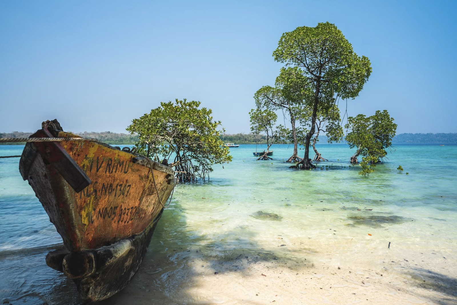 Rustic fishing boat resting on soft white sand beach and turquoise lagoon