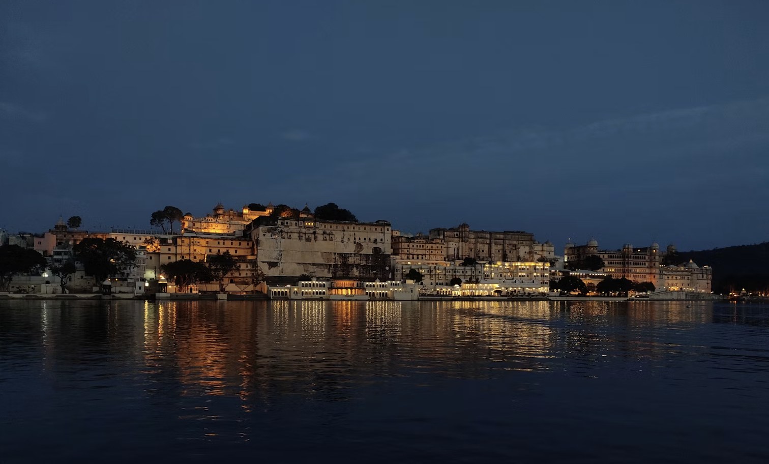 City Palace illuminated with golden evening glow reflecting across the lake