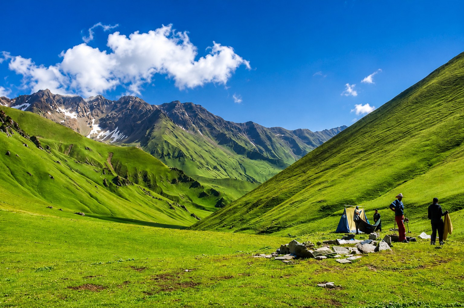 Lush green rolling meadows and trekkers camping at Dayara