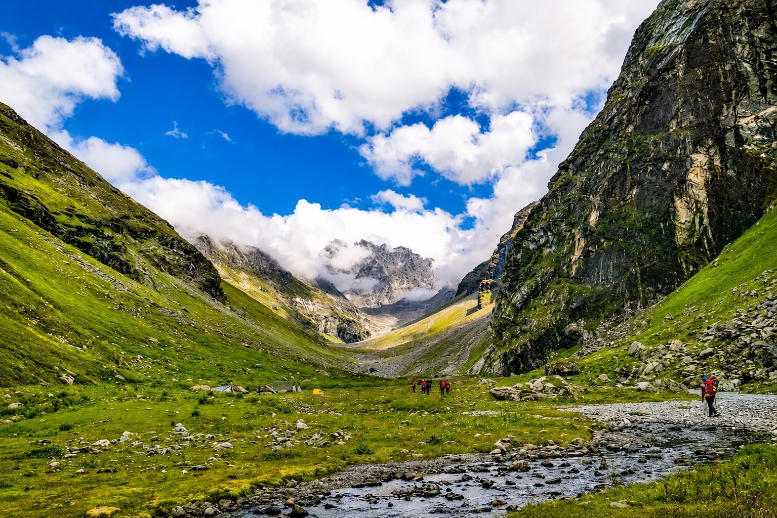 Lush green valley trails with distant snow peaks