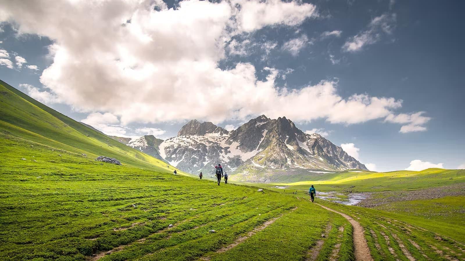 Lush rolling green meadows surrounded by mountain peaks