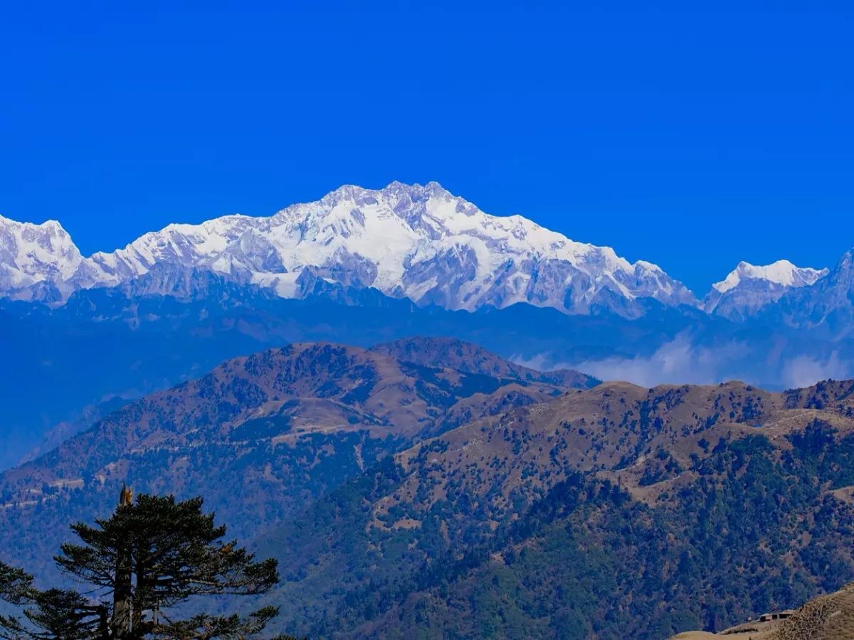 Towering snow-clad Kanchenjunga peak against crystal blue skies