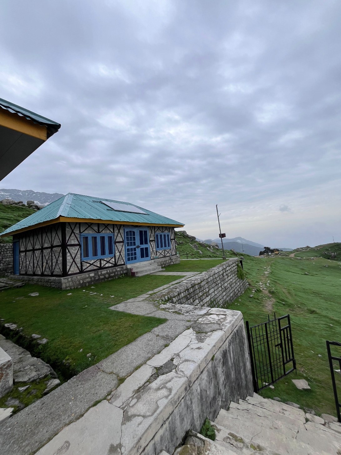 Triund top rest house with green mountain ridge and clouds